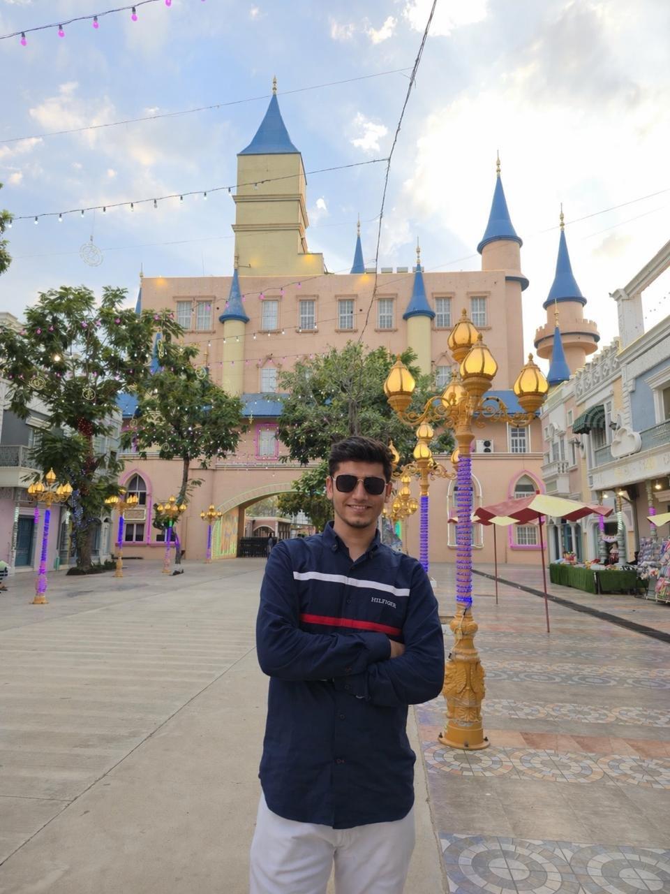 Tushar Rupani standing in front of a castle at a theme park